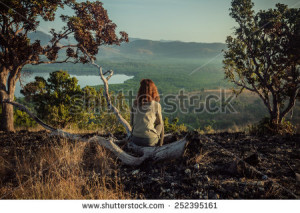 stock-photo-a-young-woman-is-sitting-on-a-hill-damaged-by-wild-fires-at-sunrise-252395161