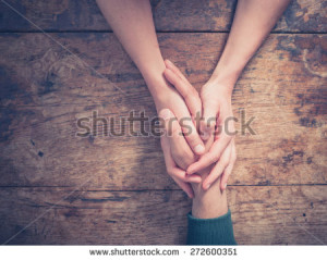 stock-photo-close-up-on-a-man-and-a-woman-holding-hands-at-a-wooden-table-272600351